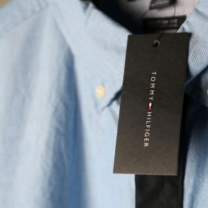 Detailed close-up of a blue dress shirt featuring a black tag with branding.